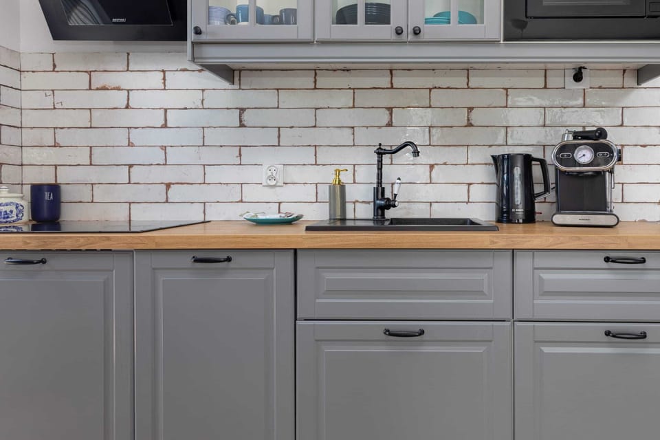 A small kitchen setup with white subway tiles, grey cabinets, and essential appliances like a coffee maker and toaster.