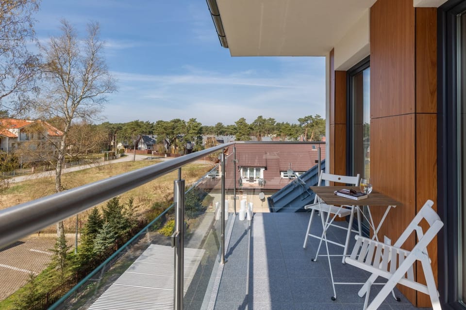 A private balcony overlooking a scenic area, furnished with a small table and foldable chairs.