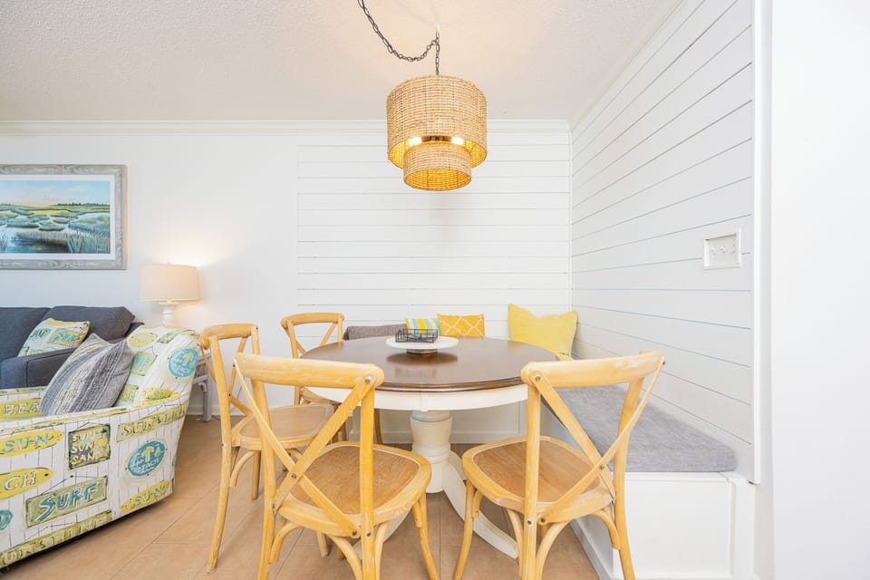 Enjoy meals at the round dining table, surrounded by light decor and a cozy bench for added comfort