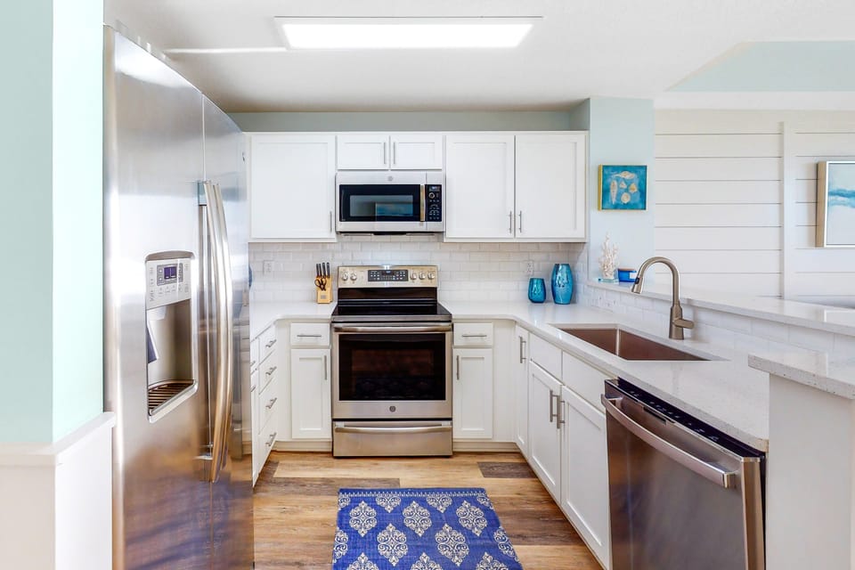 Kitchen features a full size fridge / freezer + dishwasher + stove + microwave + cooking + eating utensils and dishware!