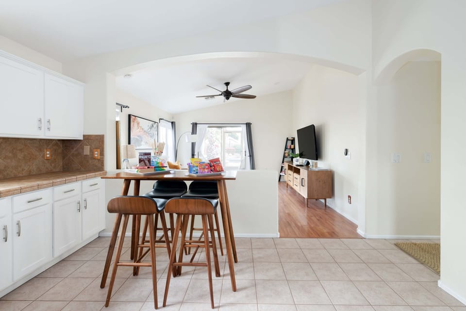 Open-concept kitchen and living area with a central island, modern bar stools, and a cozy living room setup.