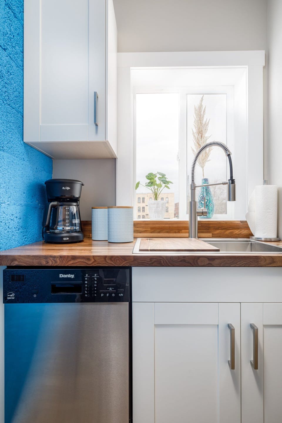 Charming coffee station by the sink w/ blue tile backsplash & window light for slow mornings.