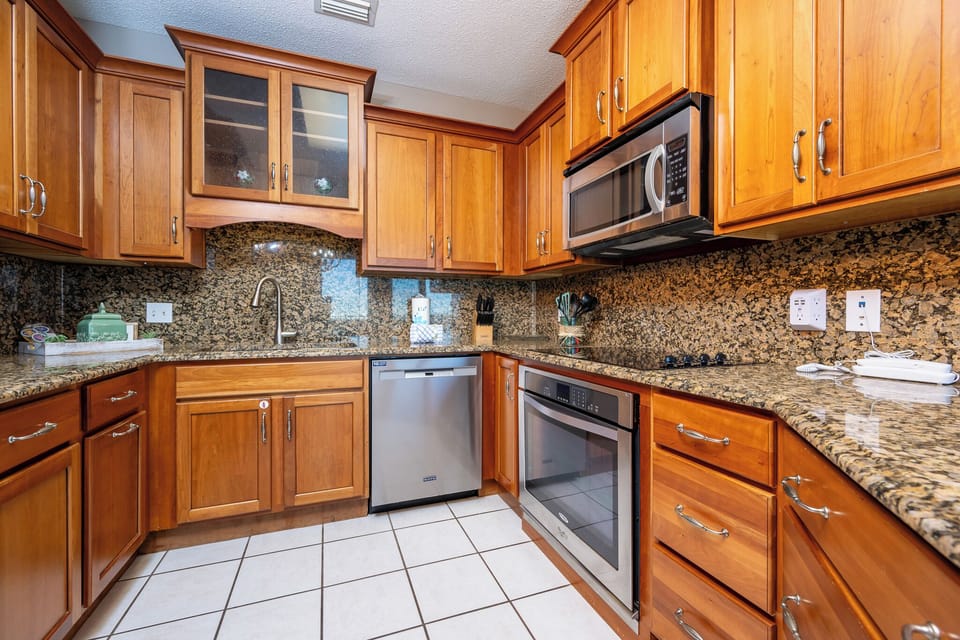 Warm wood cabinetry complements the granite countertops in this inviting kitchen, featuring modern stainless appliances