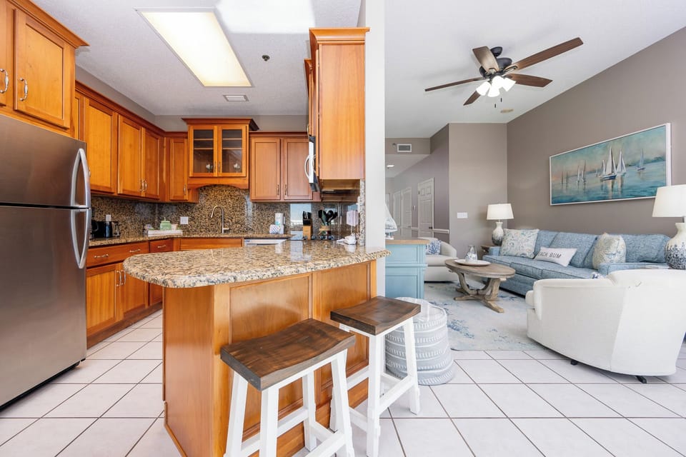 Warm wood cabinetry complements the granite countertops in this elegant kitchen, featuring a breakfast bar with seating