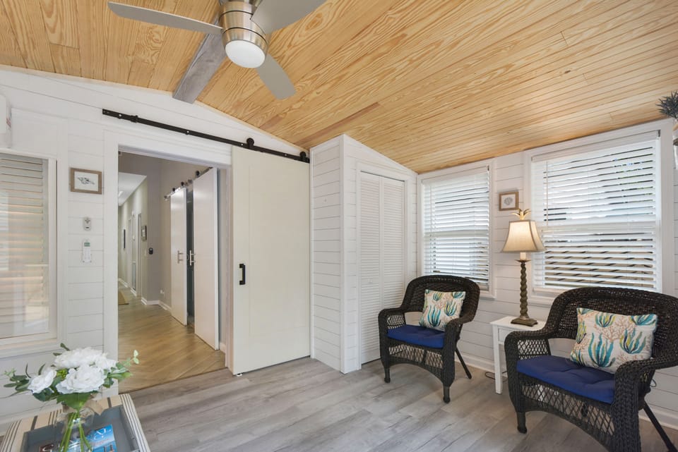 Flex Room with Pine Ceiling and Barn Door - This cozy bonus space features a vaulted pine ceiling, barn door accents, and twin armchairs perfect for a quiet read or post-beach nap. It opens directly to the deck and backyard.