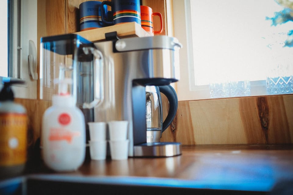 Cozy up and enjoy your morning coffee in this fully equipped kitchen featuring a modern coffee maker, fresh cups, and a charming wood finish. 