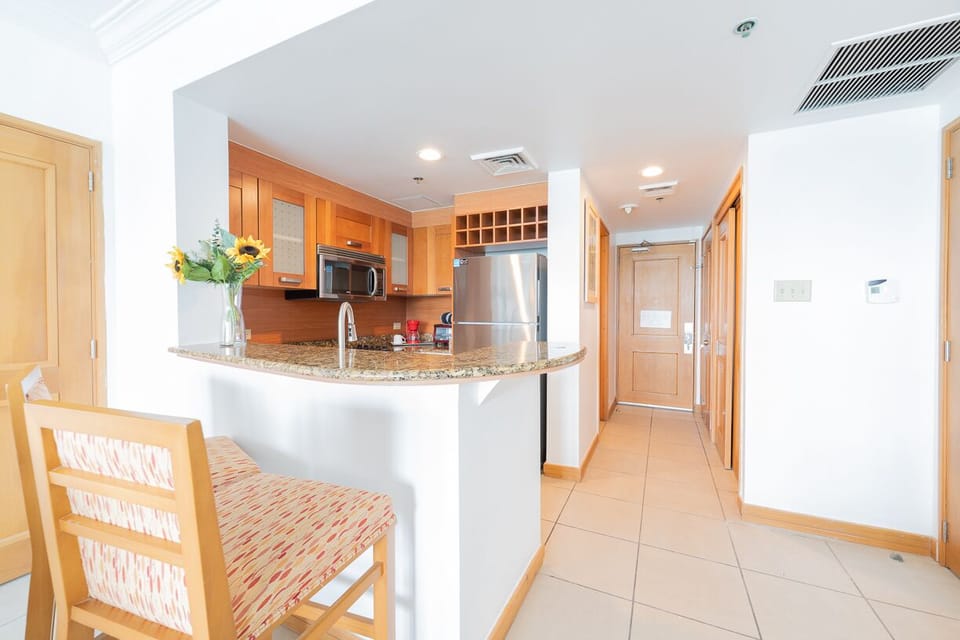 Kitchen with stove, microwave, toaster oven, bar style counter top with 2 stools