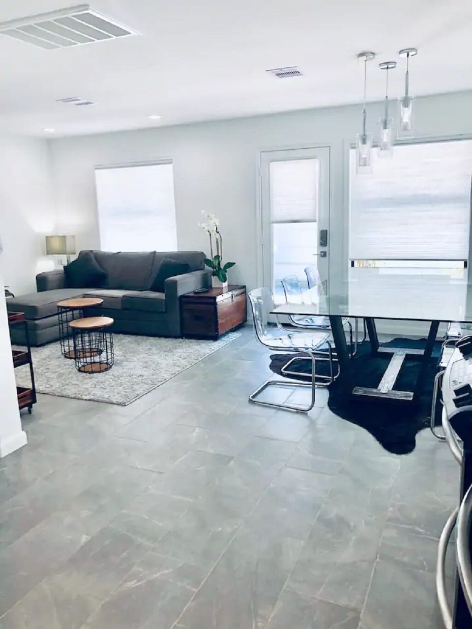 Open living/dining/kitchen with cool colors and modern furnishings.