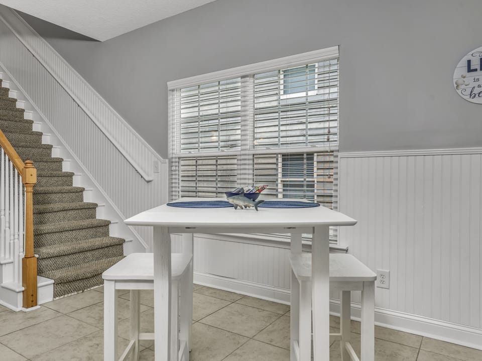 Gather around your bright breakfast nook where morning conversations flow over coffee, with coastal charm and natural light streaming through windows.