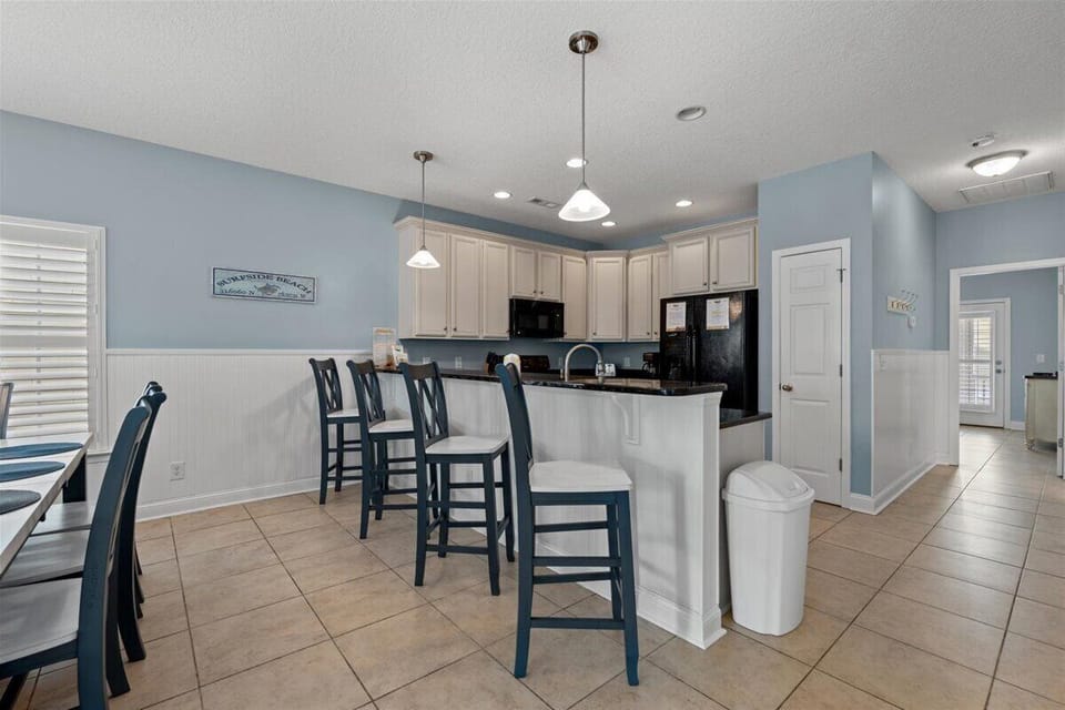 Your spacious kitchen features white cabinetry, granite countertops, and a breakfast bar where you can enjoy morning coffee overlooking the coastal-themed living area.