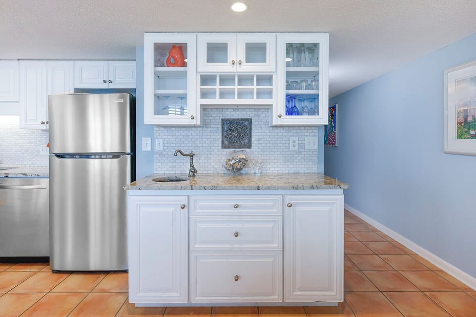Enjoy a drink from this stylish wet bar area in the kitchen featuring a stylish backsplash and elegant tile work