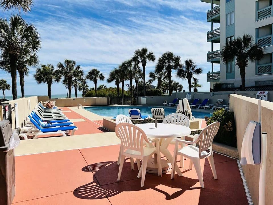 Outdoor pool w/ sunloungers and table w/ chairs