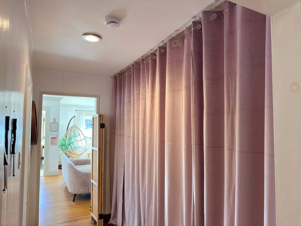 Enjoy complete seclusion at a moment’s notice with these elegant floor-to-ceiling blackout curtains and a classic rattan screen, perfect for partitioning the space into a private, cozy sanctuary.
