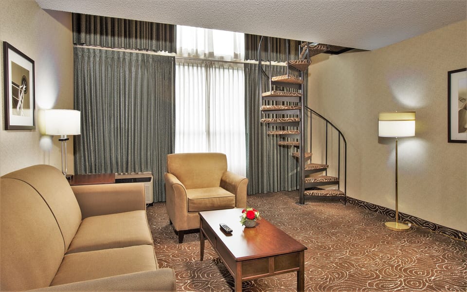 Lounge downstairs beneath soaring windows and warm lighting.
