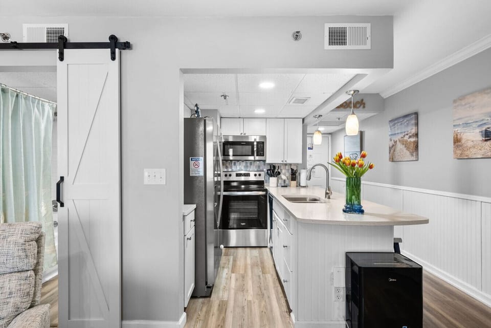 Modern coastal kitchen with stainless appliances and a spacious breakfast bar perfect for cooking and gathering.