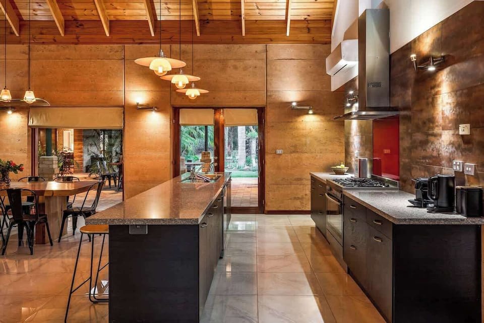 A beautiful and fully stocked kitchen with modern appliances, a red splashback, and a central island for morning chats.