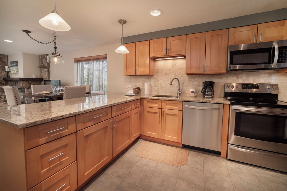 Your fully equipped kitchen features granite countertops, stainless steel appliances, and warm wood cabinetry for home-cooked meals.