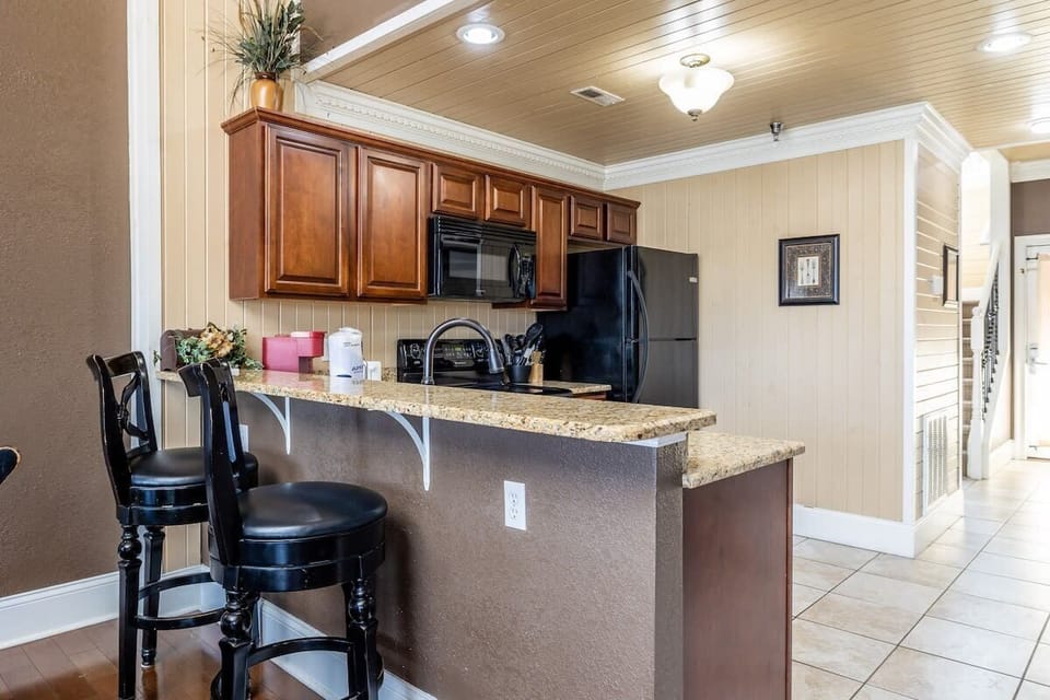 The black appliances and furniture pop against the rich wood cabinets, creating a stunning backdrop for your cooking adventures.