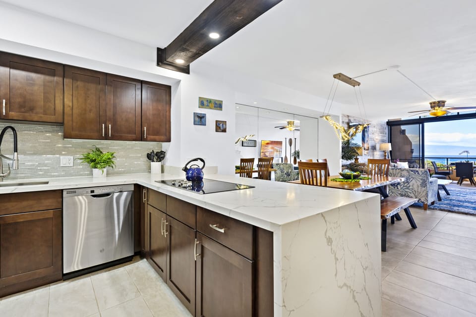 Prepare meals in this sleek, fully equipped kitchen featuring stainless steel appliances, marble countertops, and an open layout overlooking the dining and living area.
