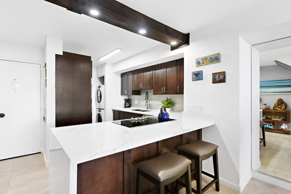 This sleek, modern kitchen features a spacious breakfast bar, stainless steel appliances, and elegant quartz countertops. Perfect for preparing meals while enjoying ocean views.