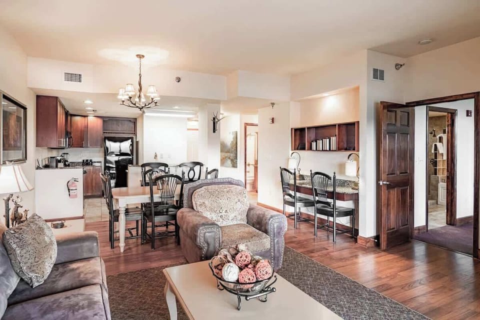 Spacious open-concept condo featuring a cozy living area, dining table, and fully equipped kitchen. Perfect for relaxing or enjoying a meal after a day of exploring. Ideal vacation rental for families or couples!