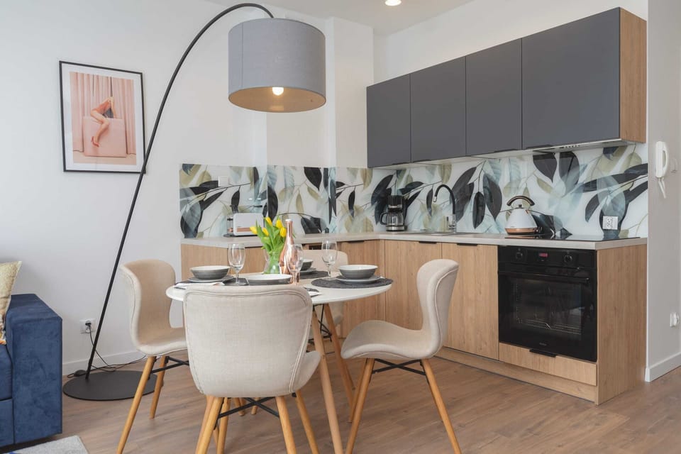 Dining space with a table set for meals and a view of the adjoining kitchenette. Fresh flowers add a welcoming touch.