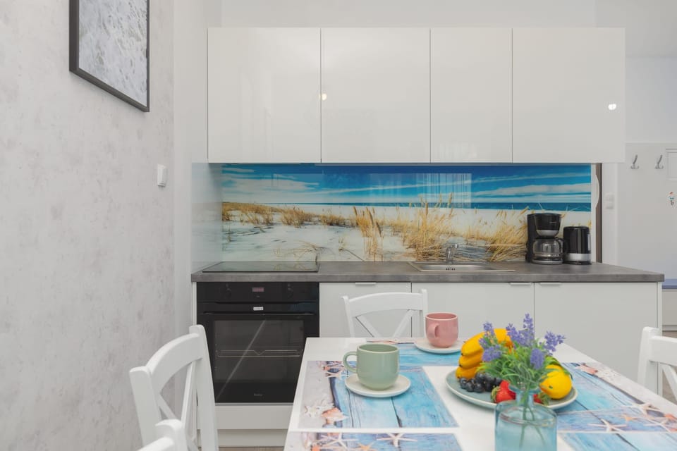 A sleek, modern kitchen with a dining table set for guests. The countertops are clean, with vibrant decor adding a pop of color.
