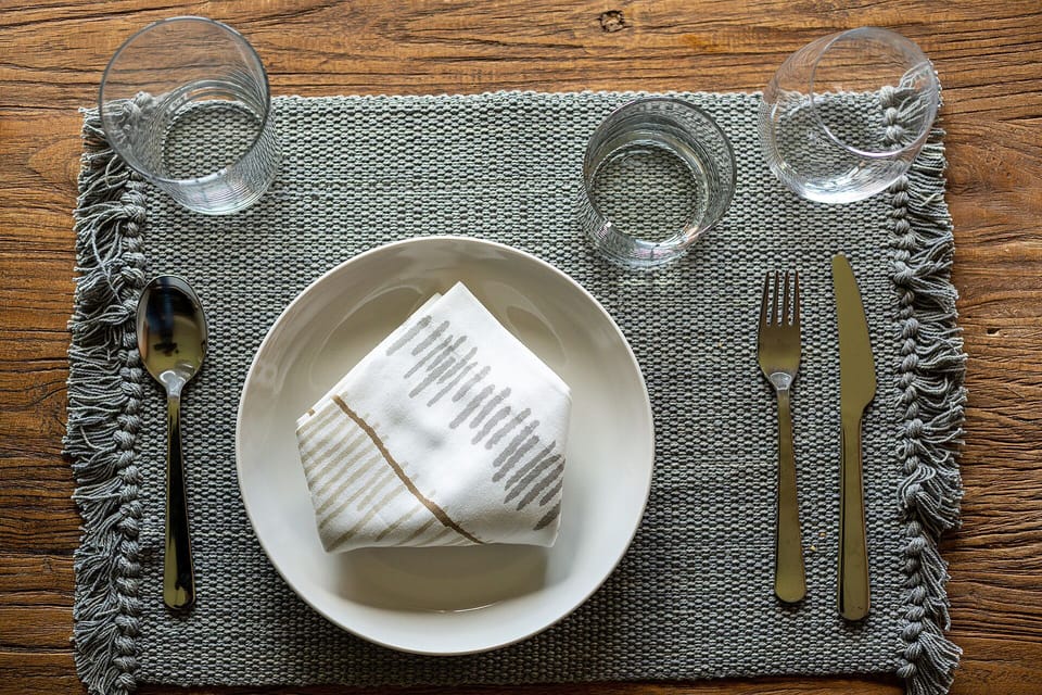 Your elegant dining setup awaits with thoughtfully arranged place settings on rich wooden surfaces, perfect for memorable meals during your stay.