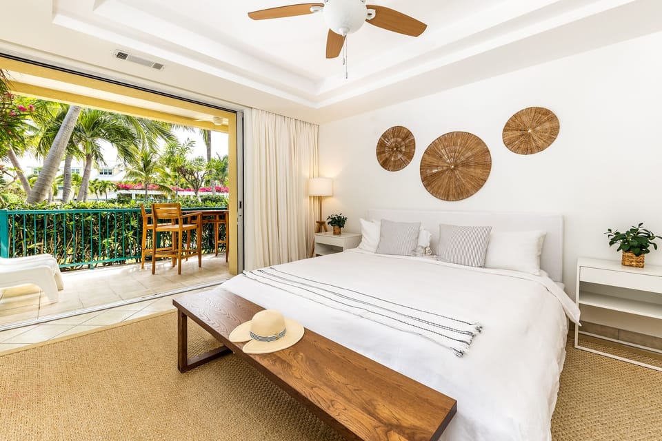 King bed, floor to ceiling sliding doors views of swaying palms and flowers