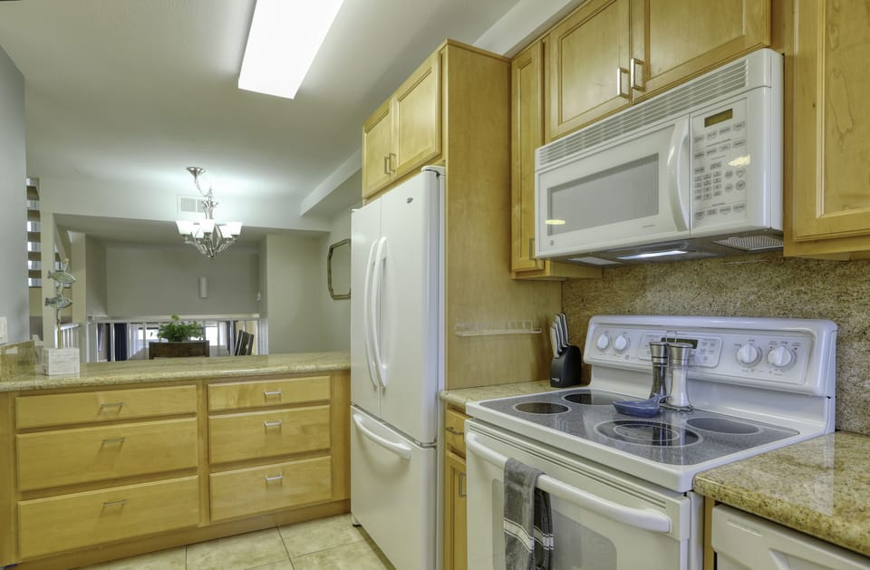 A modern electric range, large microwave and oversized refrigerator/freezer accommodate family dining and leftovers.