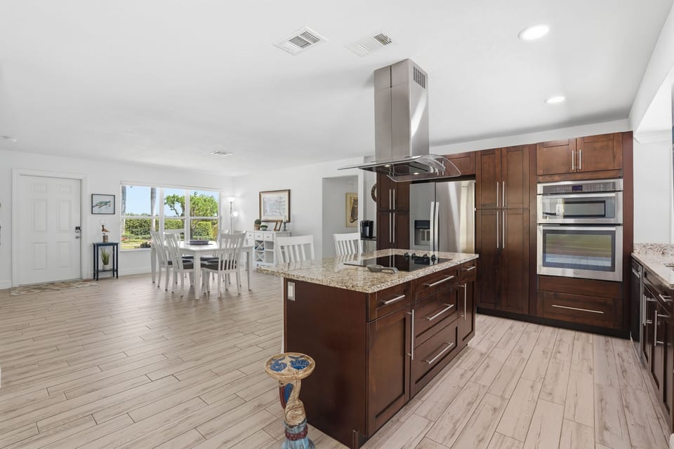Bright open kitchen with granite island, stainless appliances & dining area
