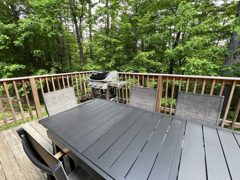 A Webber grill and large table sit on this private deck w/ seasonal water views.