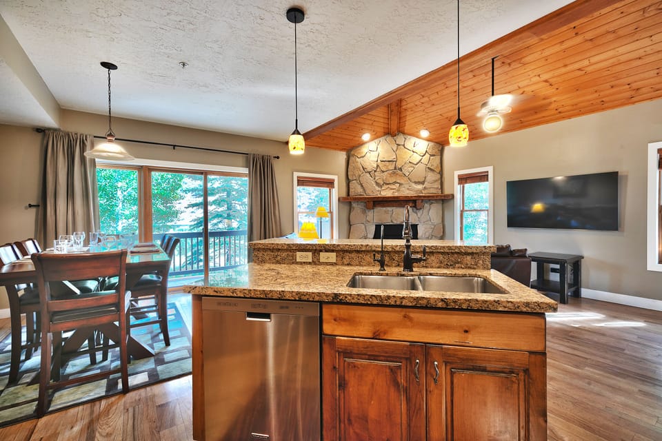 Two-tiered kitchen island with granite countertops, wooden cabinets and stainless steel dishwasher