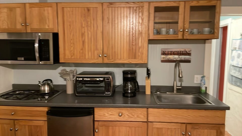 Stocked kitchen with four burner gas stove, counter top oven, and microwave.