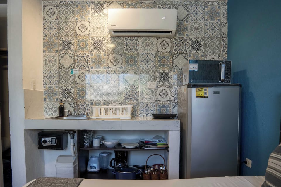Compact kitchenette with a full fridge and stylish tile, everything on hand for a simple meal in