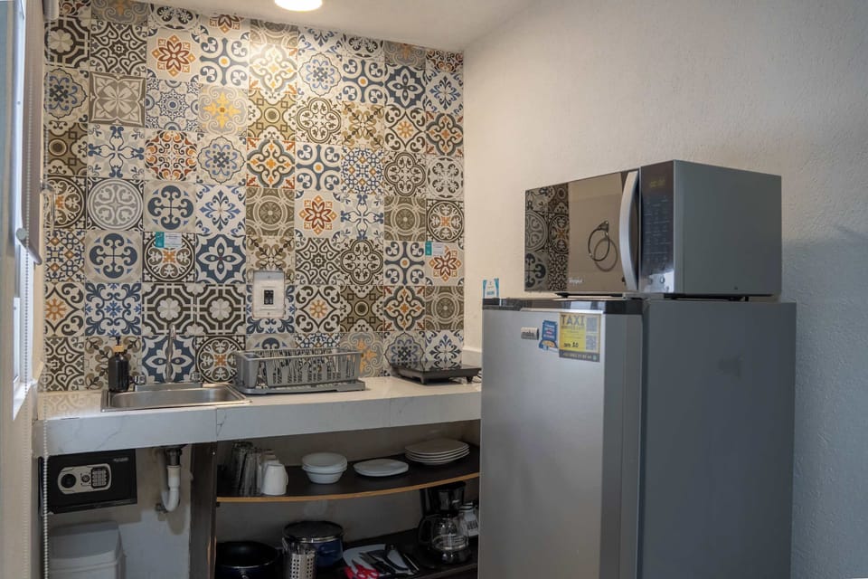 Fully equipped kitchenette with a colorful tile backsplash and fridge, everything you need to cook in