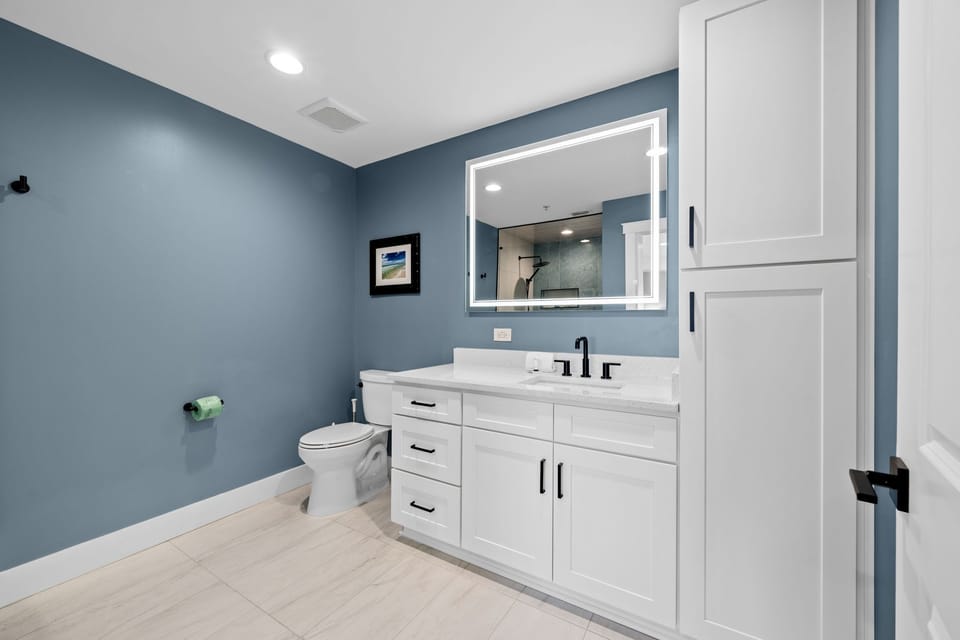 Your modern bathroom features soothing blue walls, crisp white cabinetry, and elegant marble countertops for a spa-like retreat.