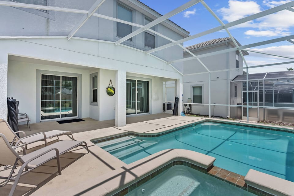 Step outside to enjoy a private pool area surrounded by a stylish screened enclosure, where you can unwind on lounge chairs and take refreshing dips in the inviting pool, perfect for relaxing under the bright sky.