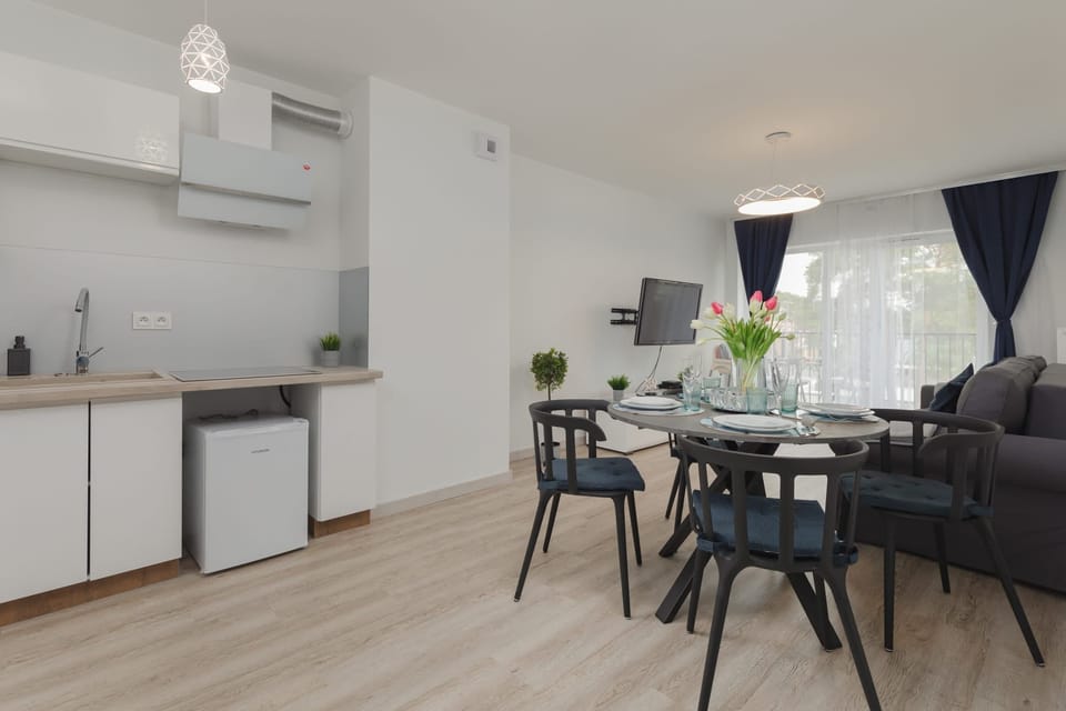Dining area with a round table set for four, featuring a simple yet elegant setup. The open layout connects seamlessly with the rest of the room.