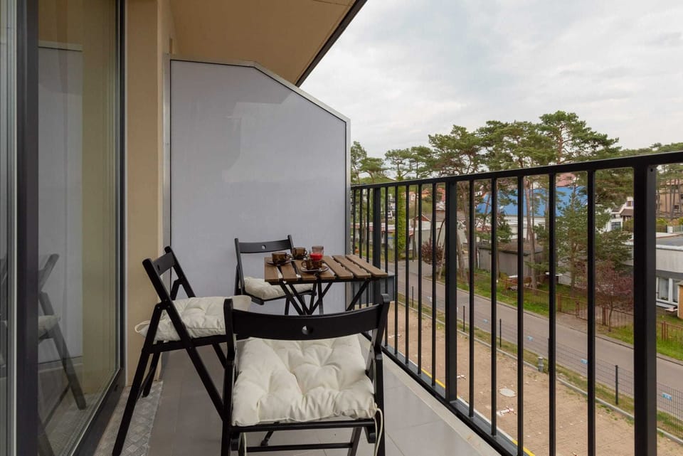 Small balcony with a table and two chairs, offering views of greenery. The setup provides a relaxing outdoor space.