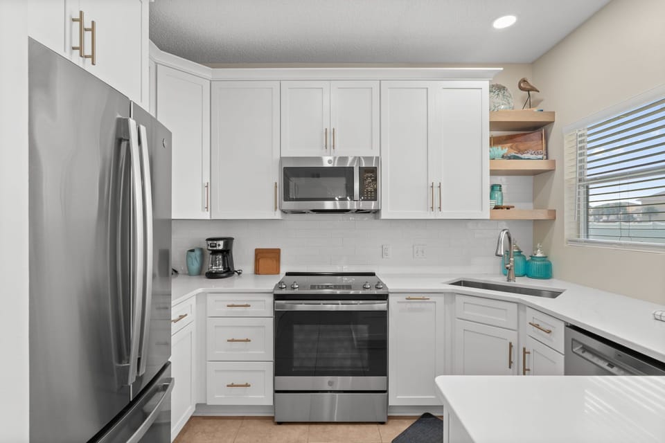 Step into your pristine modern kitchen with gleaming stainless appliances, crisp white cabinetry, and quartz countertops ready for your culinary adventures.