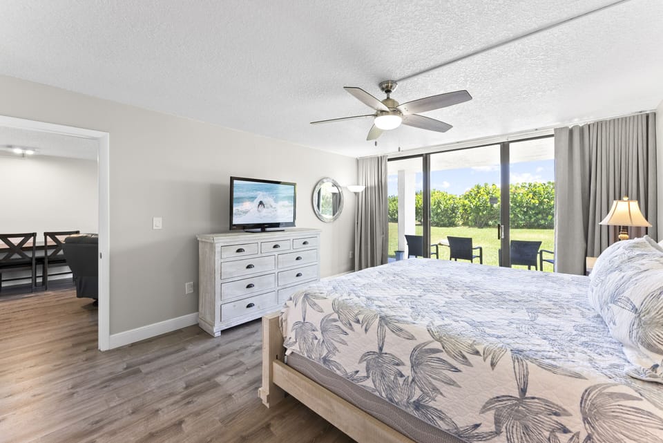 Luxurious master bedroom featuring a king bed, TV, and patio access