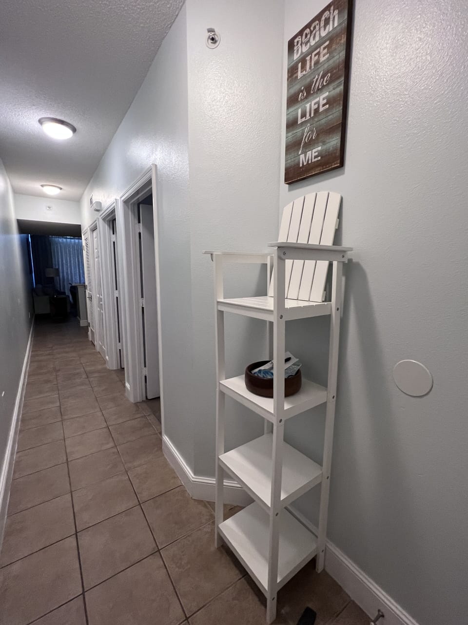 Long hallway view from the entry to the unit with shelves by the front door
