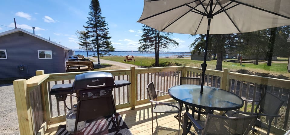 View of the lake from deck. Table and chairs, umbrella and gas grill on the deck