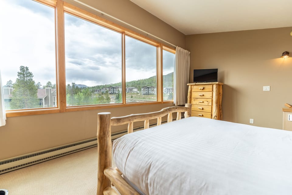 Upstairs bedroom featuring a queen bed, private bathroom, and scenic views from the windows.
