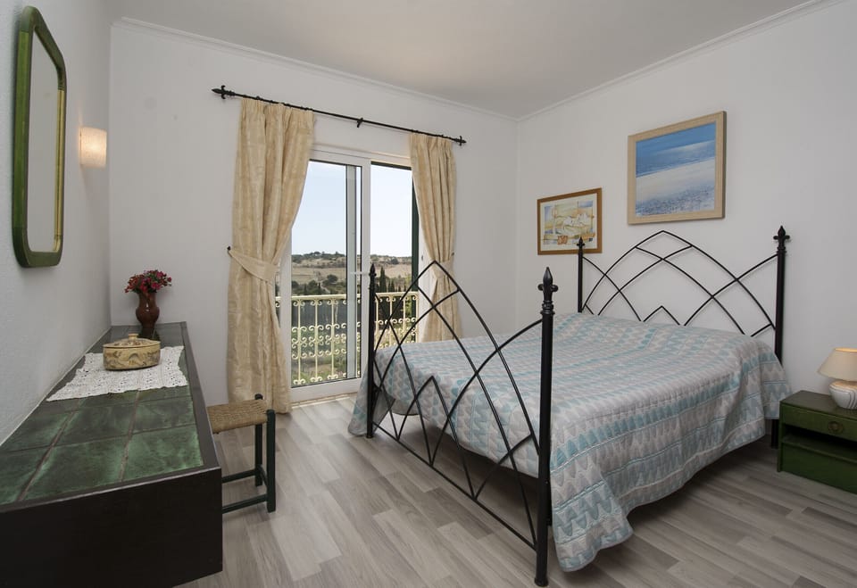 This bedroom in Villa Lorena has a double bed and a large sliding window.