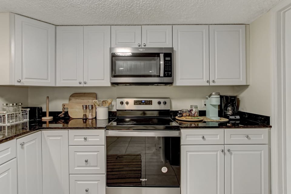 Fully Equipped Kitchen with Granite Countertops, Stainless Steel Appliances, and White Cabinetry