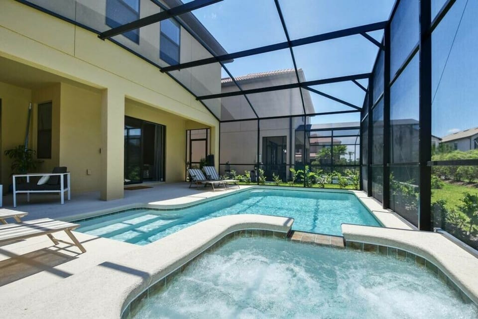 Welcome to your private oasis with a sparkling pool and soothing hot tub, all enclosed for your comfort. Relax on the sunlit patio surrounded by lush greenery, creating a serene escape in nature's beauty.