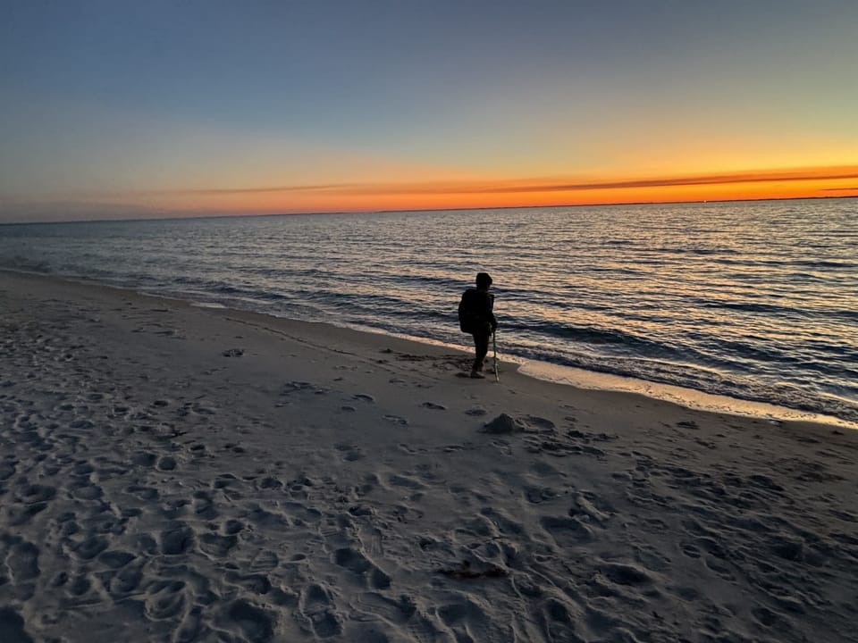 A breathtaking beach sunset with a lone traveler strolling along the shore, capturing the essence of peace and tranquility.