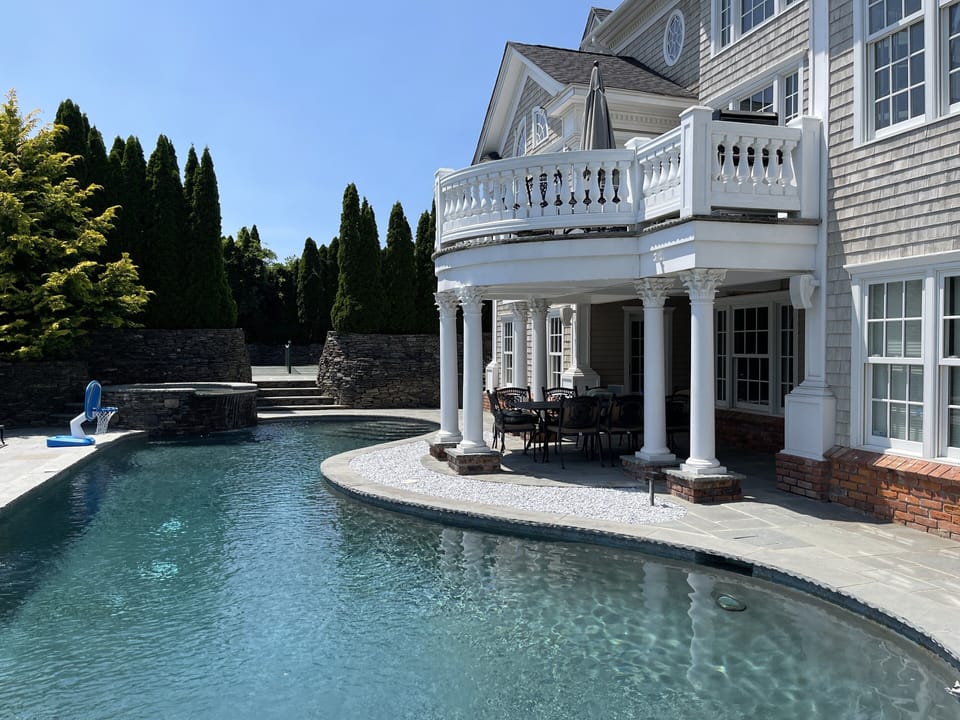 View of the back of the house, with the pool, hot tub and tennis court.